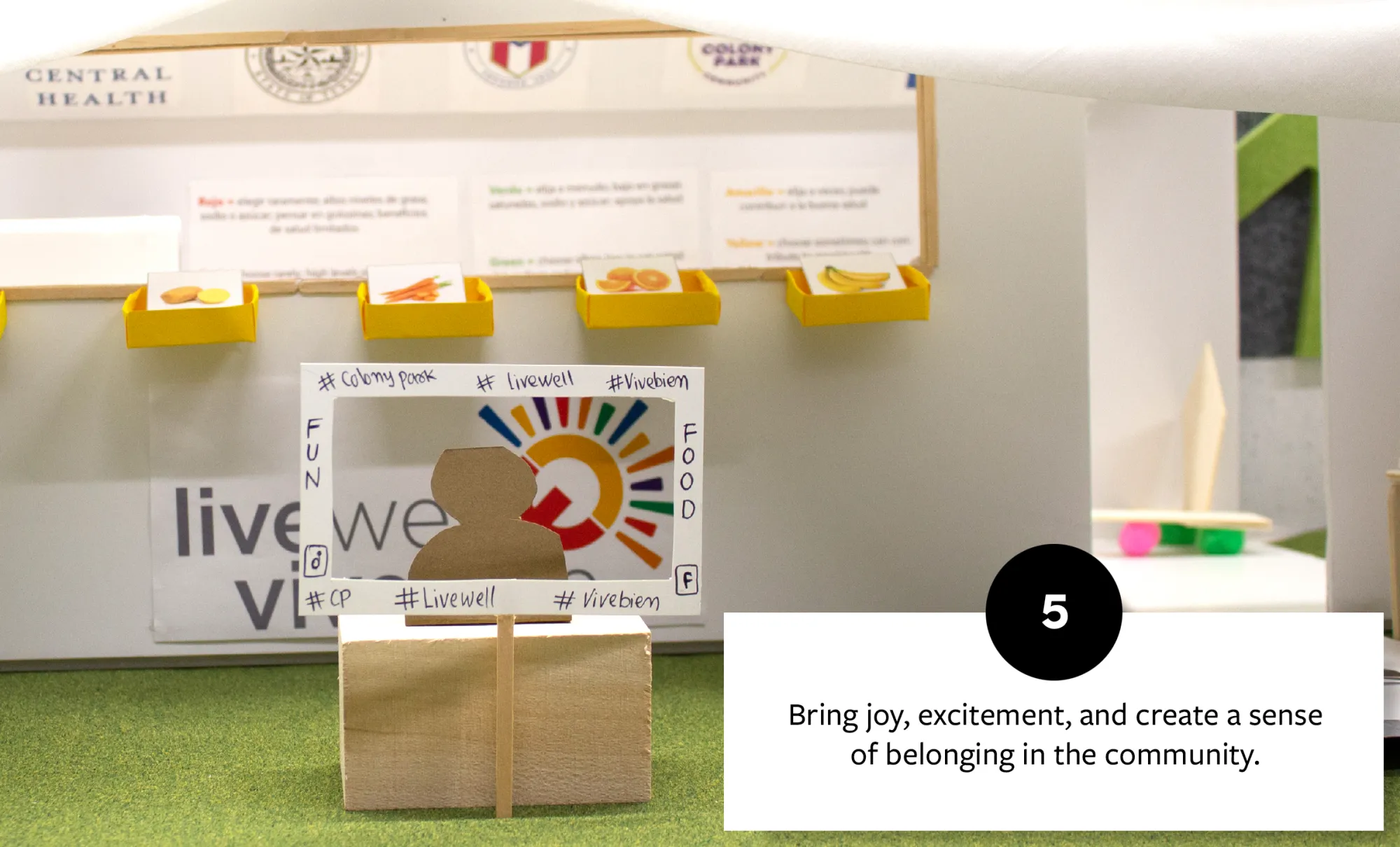 Interactive display with a cardboard figure and a cut-out photo frame, promoting a sense of community and engagement with joyful elements like colorful food images.