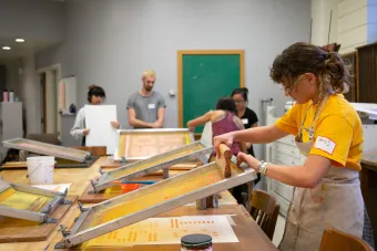 Design student screen printing a poster in the Design Lab at UT Austin