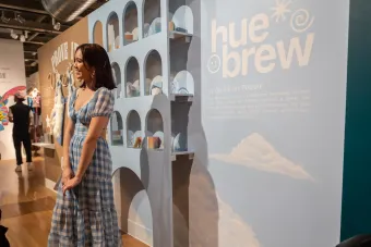 BFA Design 2022 graduate Gia Kanani Poblete smiling in front of her senior exhibition Hue Brew