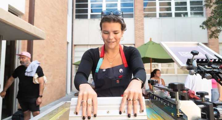 Master of Fine Arts in Design student enjoying a screen printing workshop outdoors with her MFA cohort at UT Austin